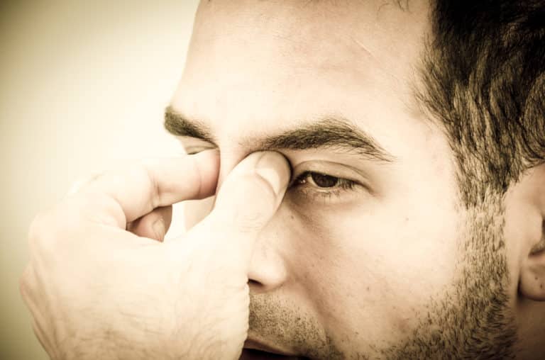 man holding his bridge of nose between eyes