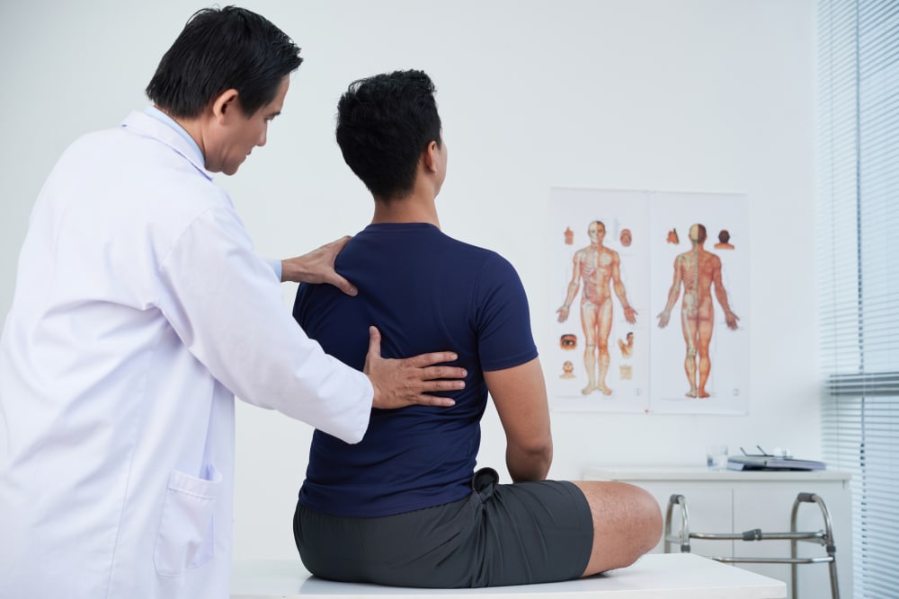Doctor checking spine of a young man